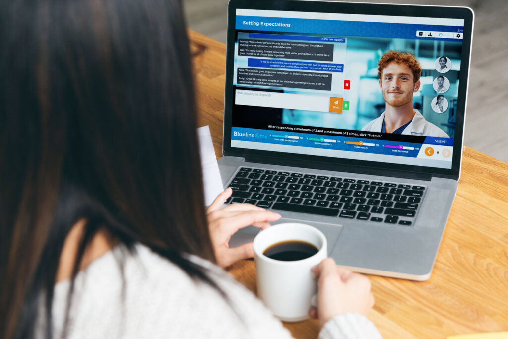 A woman with dark hair holding a white mug of coffee while sitting at a wooden table, looking at a laptop screen displaying a video call with a man and a setting expectations page.