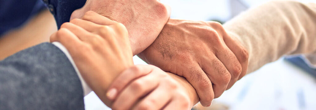 A group of diverse hands stacked together in a show of teamwork and unity.