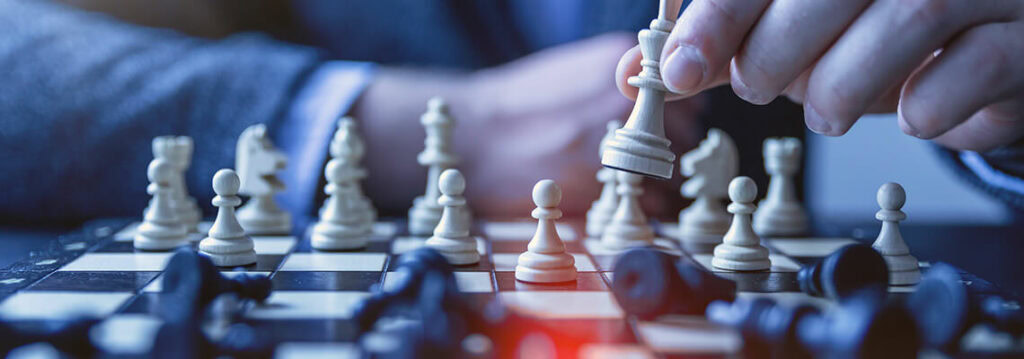 Checkmate position on a chessboard with a hand moving a white king piece. The scene emphasizes strategic gameplay and concentration during a chess match.